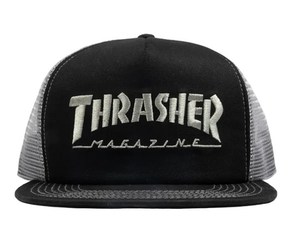 A black trucker hat with a silver embroidered 'Thrasher Magazine' logo on the front, featuring a black flat brim and gray mesh back panels, set against a plain light gray background.