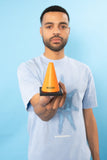 A man holds out an orange Quasi Skateboards Stress Cone, with the 'Quasi' logo visible on its side.