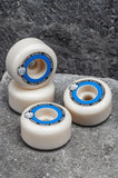 Spitfire F4 99 Tablets Wheels, white skateboard wheels with blue graphics, on a concrete background.
